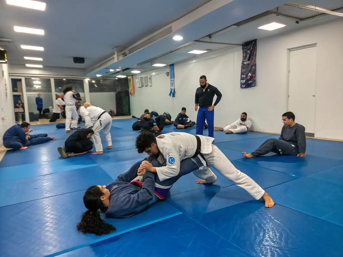 A focused image of jujitsu students practicing grappling techniques under the guidance of an instructor at JUDO CLUB RUFFECOIS.